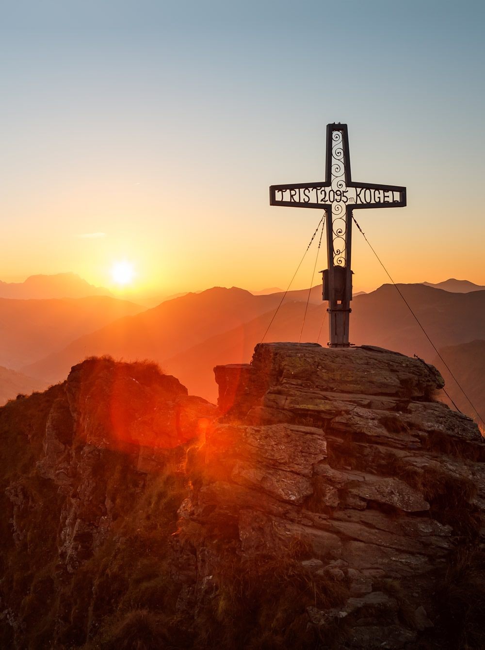 Sonnenaufgang am Gipfelkreuz in Saalbach width=
